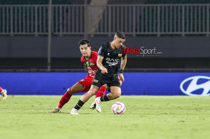 Alexis Messidoro (depan) sedang menguasai bola dan dibayangi Bruno Moreira (belakang) dalam laga pekan ke-24 Liga 1 2024 antara Dewa United FC versus Persebaya Surabaya di Stadion Pakansari, Bogor, Jawa Barat, Jumat (21/2/2025).